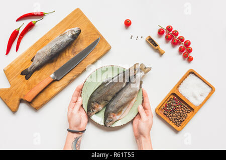 Portrait de femme en tenant la plaque avec les poissons crus de la table avec des ingrédients Banque D'Images