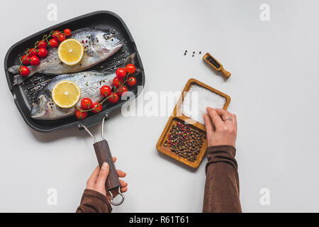 Portrait de femme de prendre le sel à table avec les poissons crus et les ingrédients dans le bac Banque D'Images