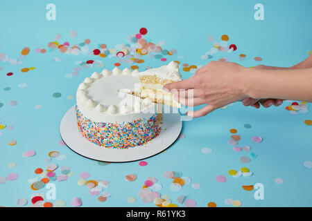 Vue partielle de la femme prenant morceau de gâteau délicieux sur fond bleu Banque D'Images