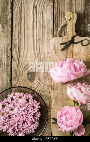 Les Pivoines et les plaques avec des fleurs sur la table en bois Vue de dessus Banque D'Images