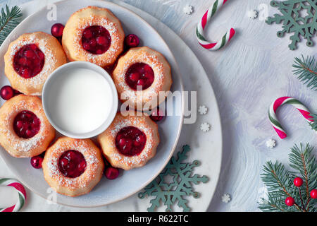 Bundt Mini gâteaux anneau avec red whortleberry confiture sur fond clair avec de petites branches de sapin, des baies et des cannes de bonbon. Maison de vacances de Noël. Banque D'Images