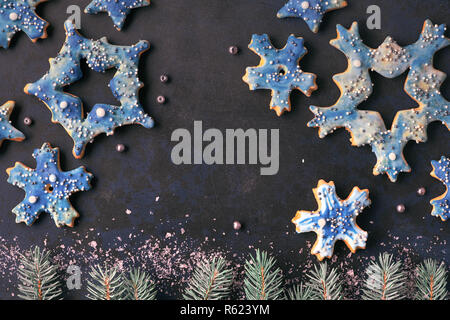 Noël arrière-plan, mise à plat et un flocon et star des cookies sur fond sombre avec de petites branches de sapin et de la neige Banque D'Images