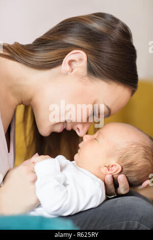 Loving Mother Cuddling Baby son nez et le touche Banque D'Images