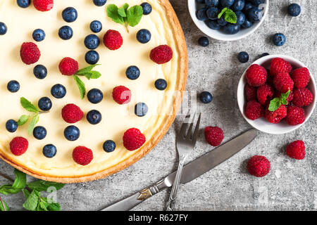 Classic New York cheesecake avec les baies fraîches, menthe et couverts sur fond de pierre, délicieux petit déjeuner vue d'en haut. Banque D'Images