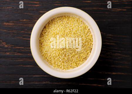 Graines de millet bio dans un bol en céramique noire en bois sur la table rustique. Le Millet peut être utilisé pour un régime alimentaire sans gluten.vue en gros plan. Banque D'Images