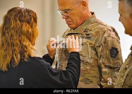 Le colonel de l'armée américaine Howard Lloyd, droite, commandant de la 28e Brigade d'aviation de combat expéditionnaire, a son grade insigne épinglé à son uniforme par son épouse lors d'une cérémonie de promotion en son honneur à la 28e 18 novembre, ECAB armory 2018. Banque D'Images