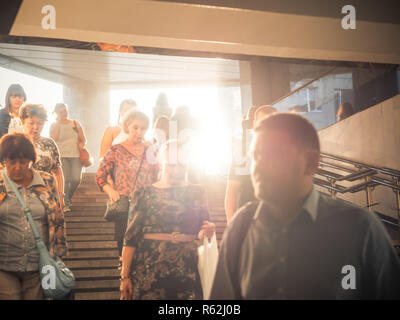 Moscou, Russie - septembre 6, 2018 : Les gens monter et descendre à la station de métro souterrain à l'heure de pointe. Les gens vont jusqu'à la bretelle. Silhouettes de personnes marchant dans les étapes contre la toile du soleil. Banque D'Images