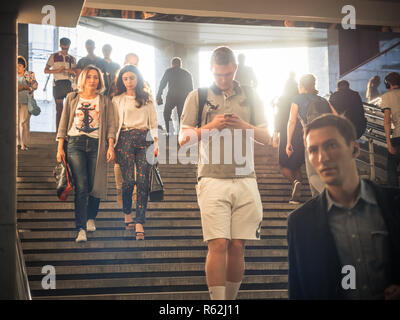 Moscou, Russie - septembre 6, 2018 : Les gens monter et descendre à la station de métro souterrain à l'heure de pointe. Les gens vont jusqu'à la bretelle. Silhouettes de personnes marchant dans les étapes contre la toile du soleil. Banque D'Images