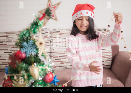 Peu asiatique girl decorating Christmas Tree pour partie avec bonheur, sélectionnez Vue profondeur de champ Banque D'Images