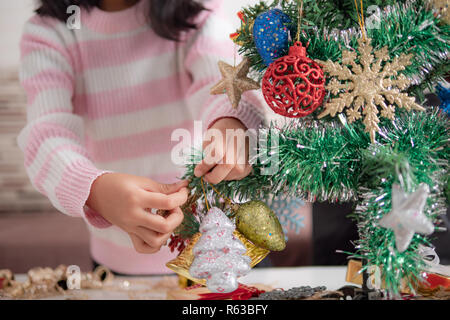 Peu asiatique girl decorating Christmas Tree pour partie avec bonheur, sélectionnez Vue profondeur de champ Banque D'Images