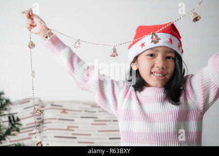 Peu asiatique girl decorating Christmas Tree pour partie avec bonheur, sélectionnez Vue profondeur de champ Banque D'Images