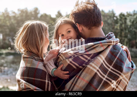 Les jeunes parents hugg leur petite fille dans la forêt d'automne près du lac. Banque D'Images