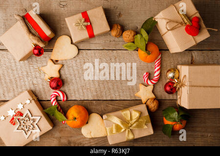 Ronde de Noël couronne de trame faite de kraft rouge doré décorations, les cookies, la mandarine, la canne de Noël sur fond de bois vintage. Mise à plat, vue du dessus, co Banque D'Images