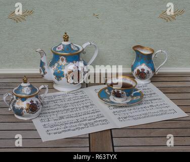 Verre d'anglais avec soucoupe, théière, sucrier et pot à crème, céramique fine porcelaine, sur une feuille de musique Banque D'Images