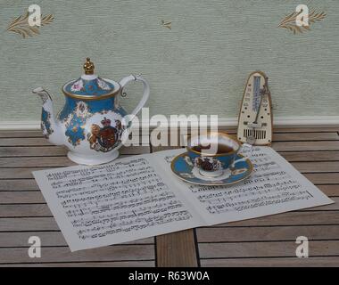 Tasse et soucoupe en anglais, théière en porcelaine fine bone China, et d'un métronome pour la musique sur une feuille de musique Banque D'Images