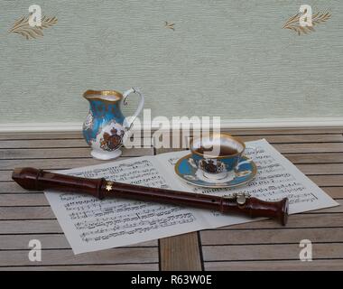 Tasse avec soucoupe, anglais cream jug, céramique fine porcelaine, et une flûte de bloc sur une feuille de musique Banque D'Images