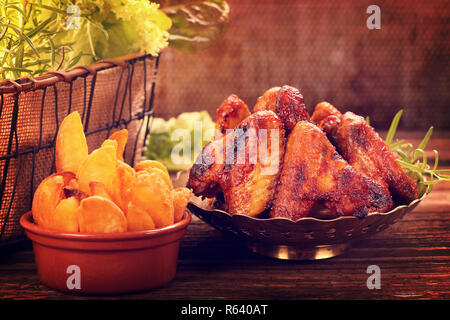 Ailes de poulet rôties avec pomme de terre au four sur la table, Close up vintage view Banque D'Images