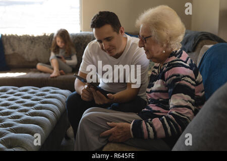 Mère et fils using digital tablet on sofa in living room Banque D'Images