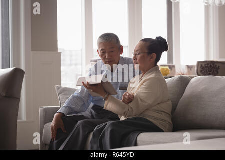 Senior couple discutant sur une tablette numérique sur le canapé dans la salle de séjour Banque D'Images