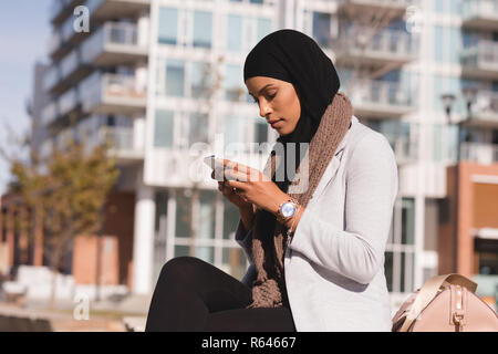 Hijab woman using mobile phone dans la ville Banque D'Images