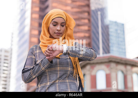 Femme à l'aide de smart watch en ville Banque D'Images