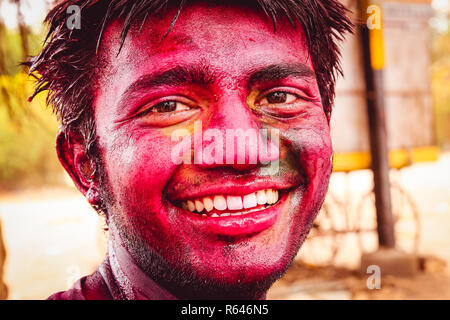 New Delhi, Inde - 10 mars 2016 : close up portrait of young, heureux, l'homme indien avec un grand sourire et le visage plein de poudre de couleur à la caméra dans duri Banque D'Images