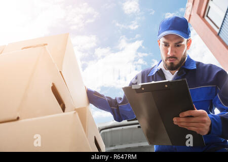 Travailleur homme debout près de boîte en carton Holding Clipboard Banque D'Images