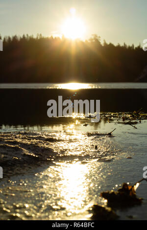 Soleil nouvellement augmenté se reflète en partie sur un lac gelé, la création d'une ligne de différentes du soleil. Bien visible en haut de l'image. Banque D'Images