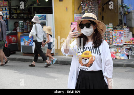 Hoi An Vietnam - Une touriste asiatique portant un masque de visage prend une photo selfies sur son téléphone dans la vieille ville de Hoi An en 2018 Banque D'Images
