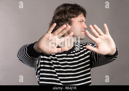 Portrait de jeune homme déplut à élever les mains devant pour dire non, s'arrêter juste là, isolé sur fond gris. Se concentrer sur les mains. Les droits négatifs emoti Banque D'Images