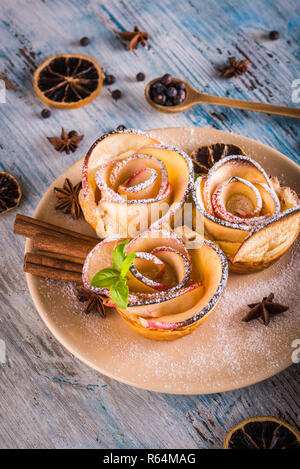 Photo verticale avec croustillant de dessert. Sweet est fabriqué à partir des tranches de pomme et de pâte feuilletée. Le dessert est appelé apple roses. Plusieurs herbes et épices sont spill Banque D'Images