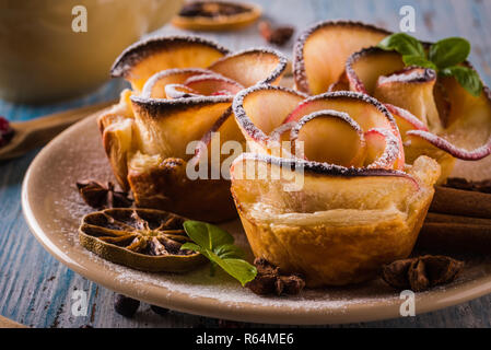 Photo horizontale avec croustillant de dessert. Sweet est fabriqué à partir des tranches de pomme et de pâte feuilletée. Le dessert est appelé apple roses. Plusieurs herbes et épices sont spi Banque D'Images