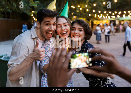 Groupe de professionnels multhiethnic friends avec un gâteau à l'extérieur, prendre photo avec photo caméra Banque D'Images