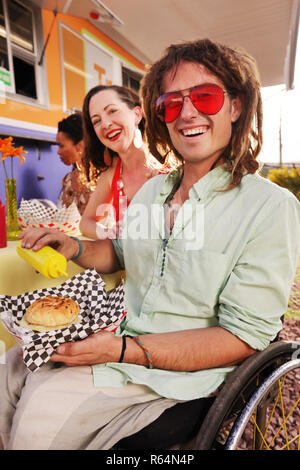 Homme handicapé ayant un hamburger pour le déjeuner Banque D'Images