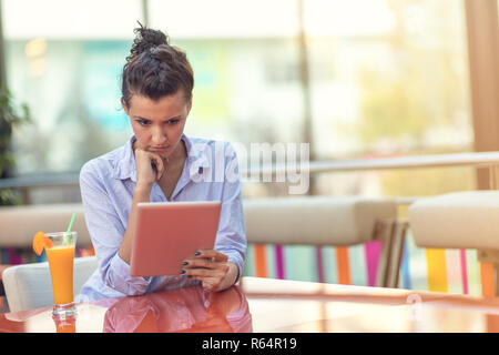 Belle mixed race woman avec une coiffure afro holding a digital tablet at coffee shop Banque D'Images