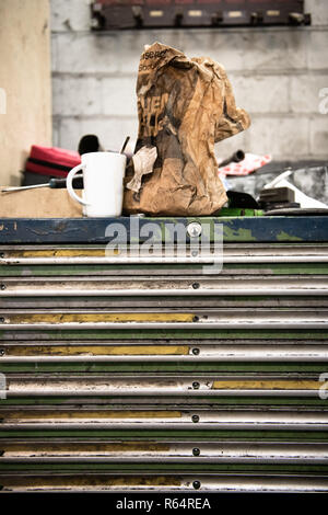 Sac de papier de petit-déjeuner et café tasse dans un garage automobile. Banque D'Images