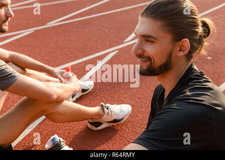 Photo de deux jeunes frères jumeaux sportifs assis dans le stade à l'extérieur. Banque D'Images