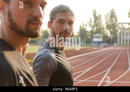 Photo de deux jeunes frères jumeaux sportifs debout à l'extérieur du stade. Banque D'Images