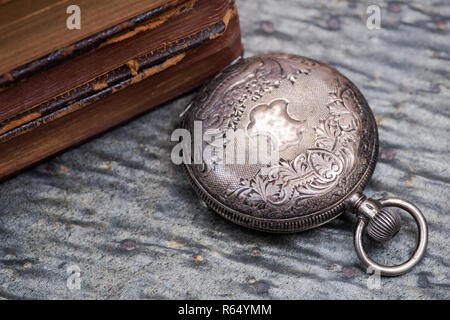 Panta rhei concept : montre de poche antique et la pile de livres à couverture rigide vintage sur fond de pierre naturelle. Banque D'Images