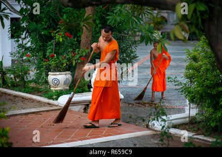 Monks balayant le sol. Wat Sene Souk Haram Wat Sen temple bouddhiste, Province de Luang Prabang, Laos, Louangphabang Banque D'Images