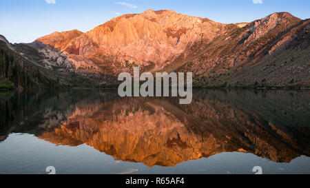 Panorama de la lumière dorée du soleil sur les sommets de montagnes, reflétée dans les eaux calmes du lac condamné dans les montagnes de la Sierra Nevada de Californie Banque D'Images