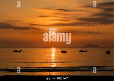 Un orange-feu lever du soleil ciel surplombant la mer de Chine du sud à Lam Bay au Vietnam. Avec un bateau de pêche en silhouette. Banque D'Images