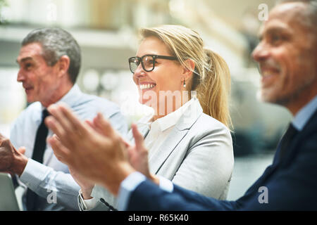 Trois smiling mature woman clapping hands assis ensemble à une table lors d'un office présentation Banque D'Images