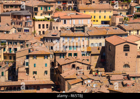 Vue sur le toit de la vieille pierre, le stuc, les bâtiments en brique et avec des volets colorés dans un paysage urbain très dense dans la ville médiévale de Sienne, Italie Banque D'Images