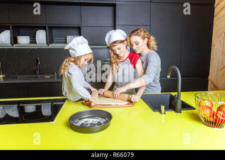 Famille heureuse dans la cuisine. La mère et les deux enfants de la préparation de la pâte, faire cuire la tarte aux pommes. Maman et les filles de la cuisson des aliments sains à la maison et avoir du plaisir. Chambre Banque D'Images