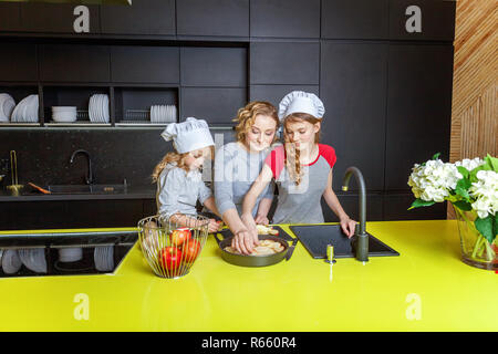 Famille heureuse dans la cuisine. La mère et les deux enfants de la préparation de la pâte, faire cuire la tarte aux pommes. Maman et les filles de la cuisson des aliments sains à la maison et avoir du plaisir. Chambre Banque D'Images