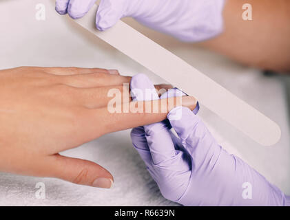 Woman getting une hygiène manucure avec lime à ongles à nail salon Banque D'Images