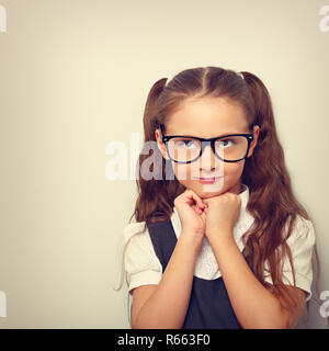 Élève grimaçante girl with long hair style dans la mode lunettes en uniforme faisant rêver à la physionomie et le haut. Tons vintage portrait gros plan Banque D'Images