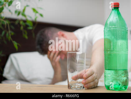 L'homme de boire l'eau minérale et souffrant de gueule de bois. Banque D'Images