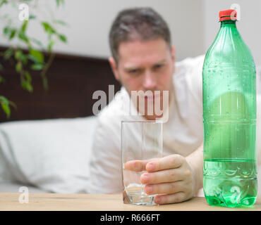 L'homme de boire l'eau minérale et souffrant de gueule de bois. Banque D'Images